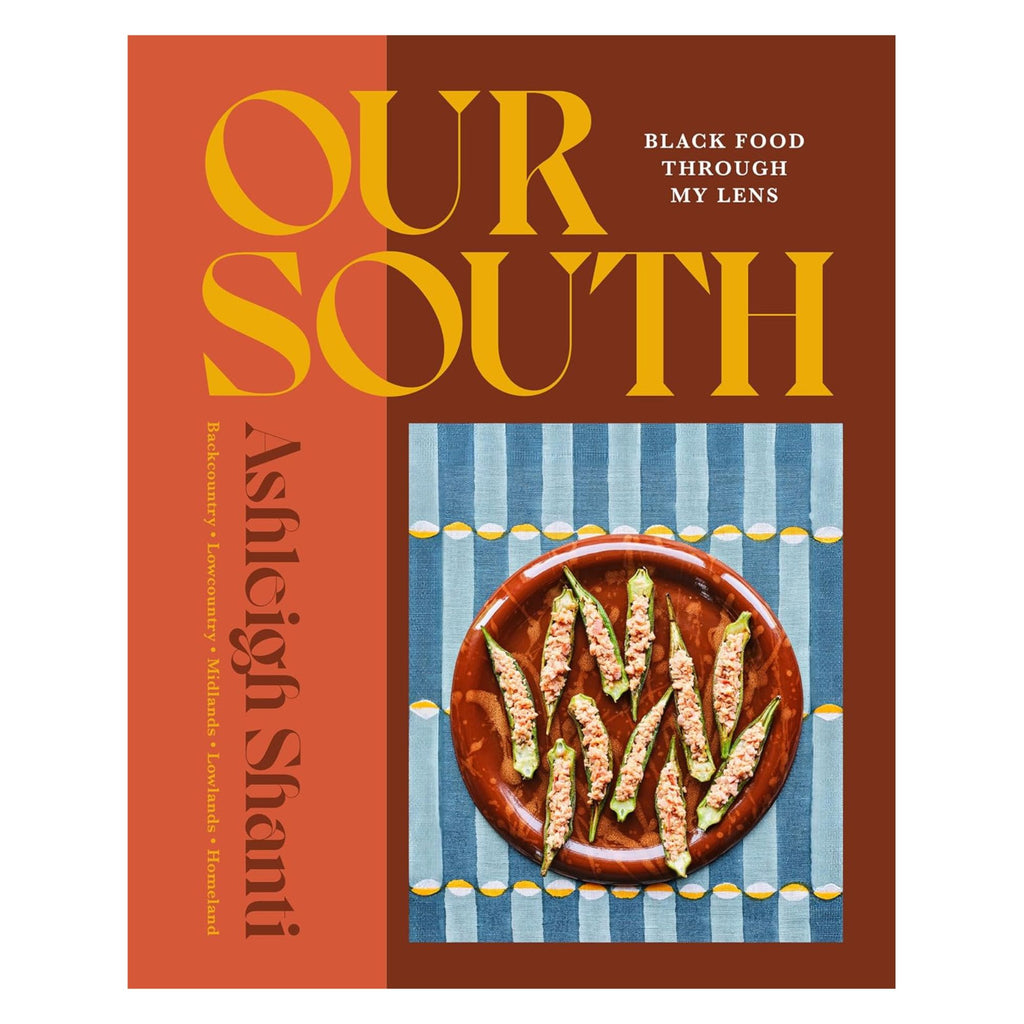 Cover of the book "Our South: Black Food Through My Lens" by Ashleigh Shanti. The design features bold orange and brown colors with blue text and a photo of a dish with stuffed okra on a brown plate, celebrating Southern cuisine, set on a blue and yellow patterned background, from the brand Gneiss Spice.