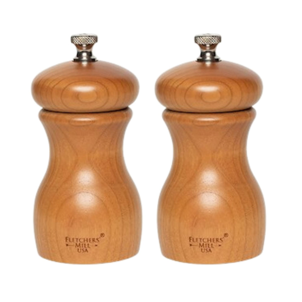 The Marsala Salt & Pepper Mill Set by Gneiss Spice showcases two wooden grinders with a smooth, curved design, metal knobs on top, and an adjustable coarseness setting. These mills exemplify durable craftsmanship for every culinary enthusiast.