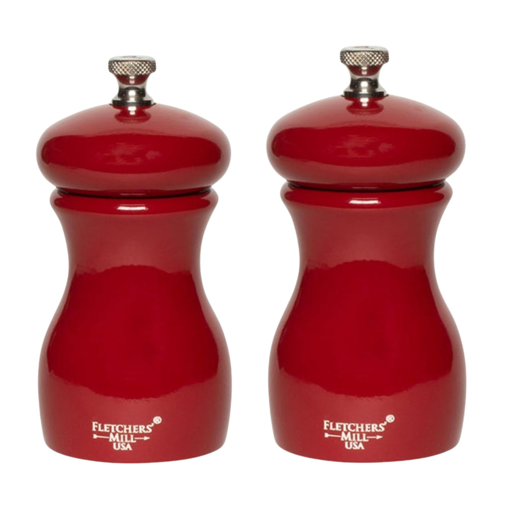 Two red Gneiss Spice Marsala salt and pepper mills, featuring durable craftsmanship, stand side by side. With a glossy finish and metal knobs on top, these grinders offer adjustable coarseness for precision seasoning. The brand name is printed near the base of each mill.