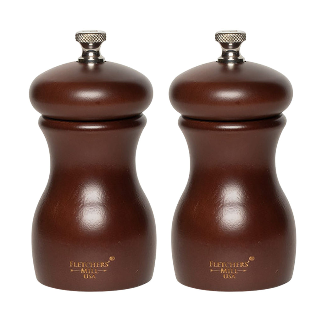 The Marsala Salt & Pepper Mill Set from Gneiss Spice features two wooden grinders showcasing durable craftsmanship with a classic, rounded shape and metal knobs on top. Finished in dark brown, this set is complemented by the brand name engraved near the base and includes adjustable coarseness for precise seasoning.