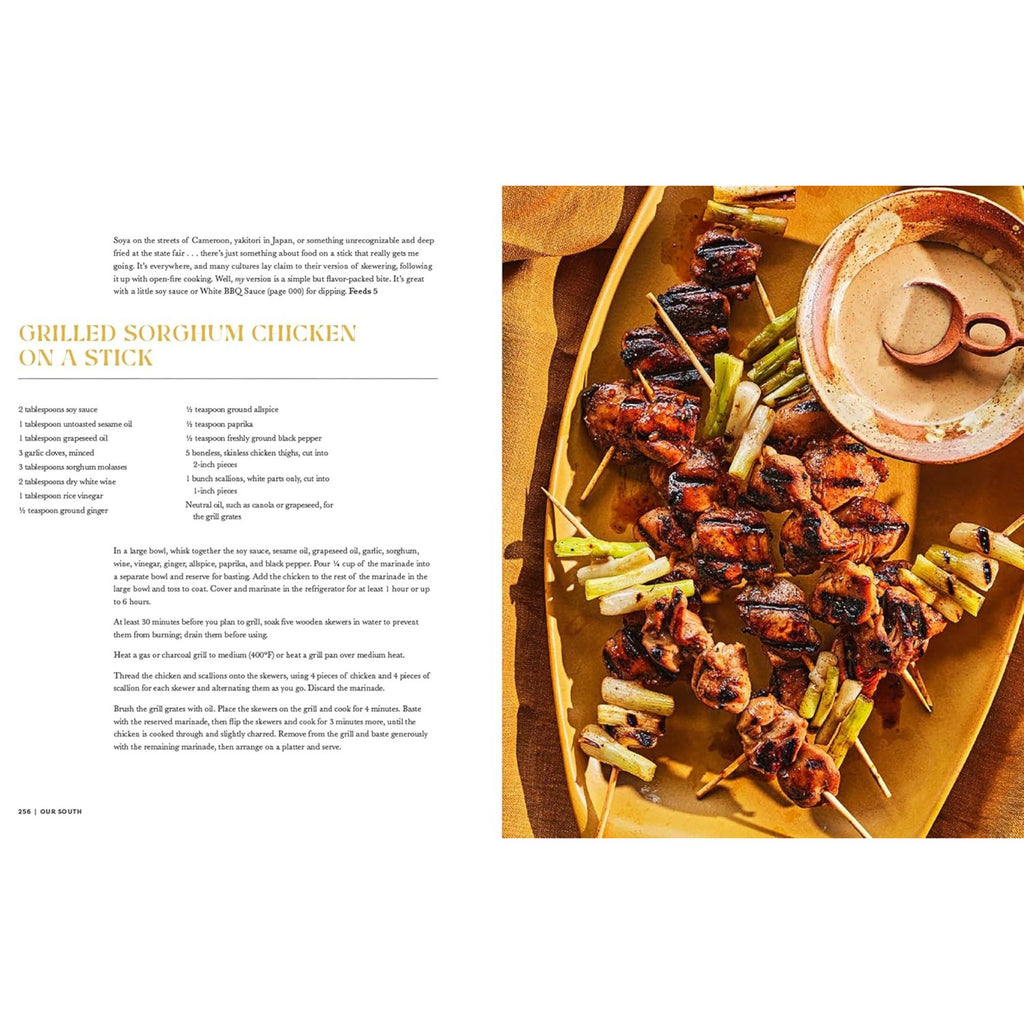 A page from "Our South: Black Food Through My Lens" by Gneiss Spice features elegantly arranged grilled sorghum chicken skewers, garnished with sliced green onions as a tribute to Southern cuisine. A small bowl of dipping sauce complements the dish. The left side of the page provides the recipe and instructions, celebrating regional traditions in every bite.