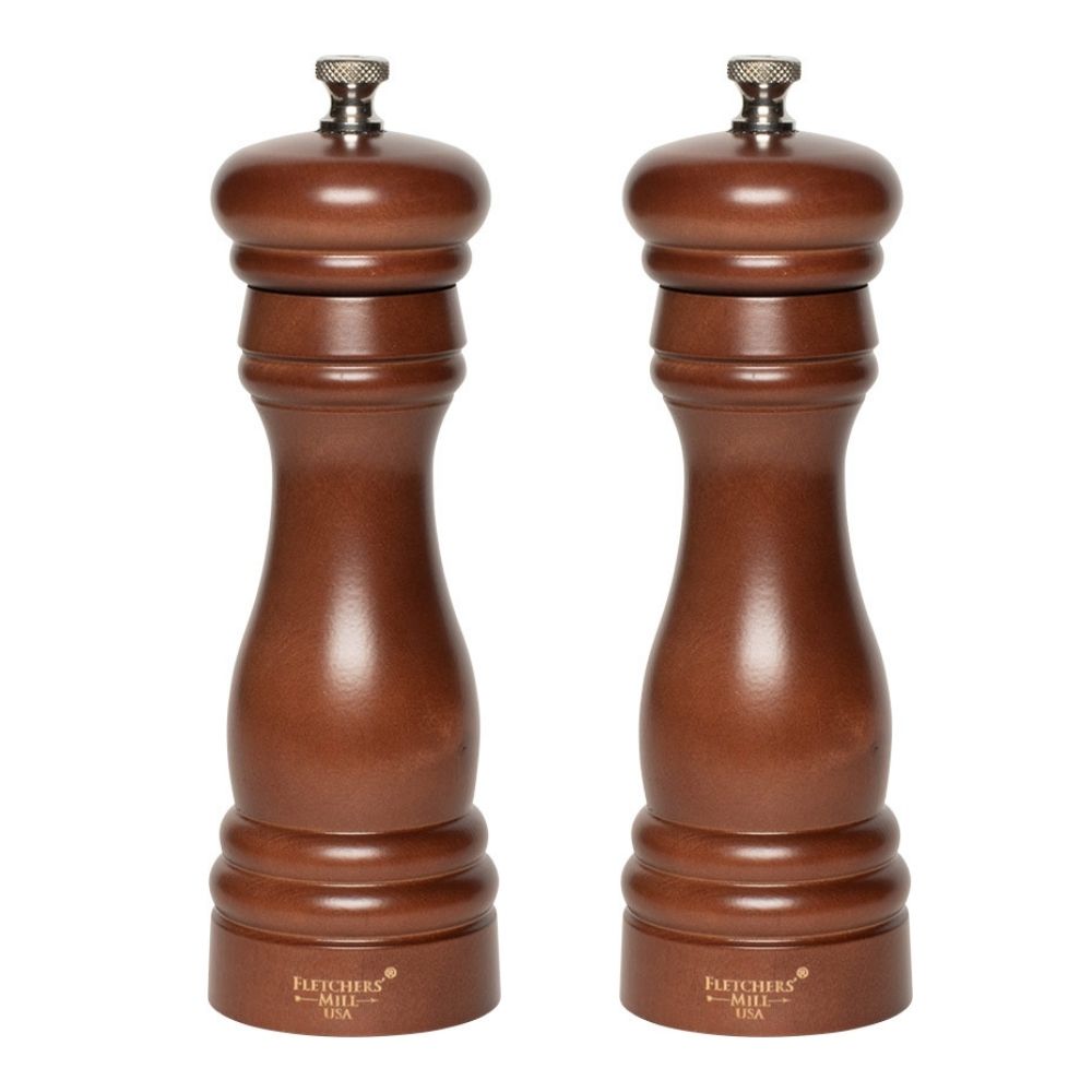 The Grinder Gift Set by Gneiss Spice features two elegantly designed pepper mills, crafted from sustainably-harvested wood with a rich brown finish and rounded tops. The brand's engraved text near the base enhances their sophisticated look, making them a beautiful addition to any dining setting.