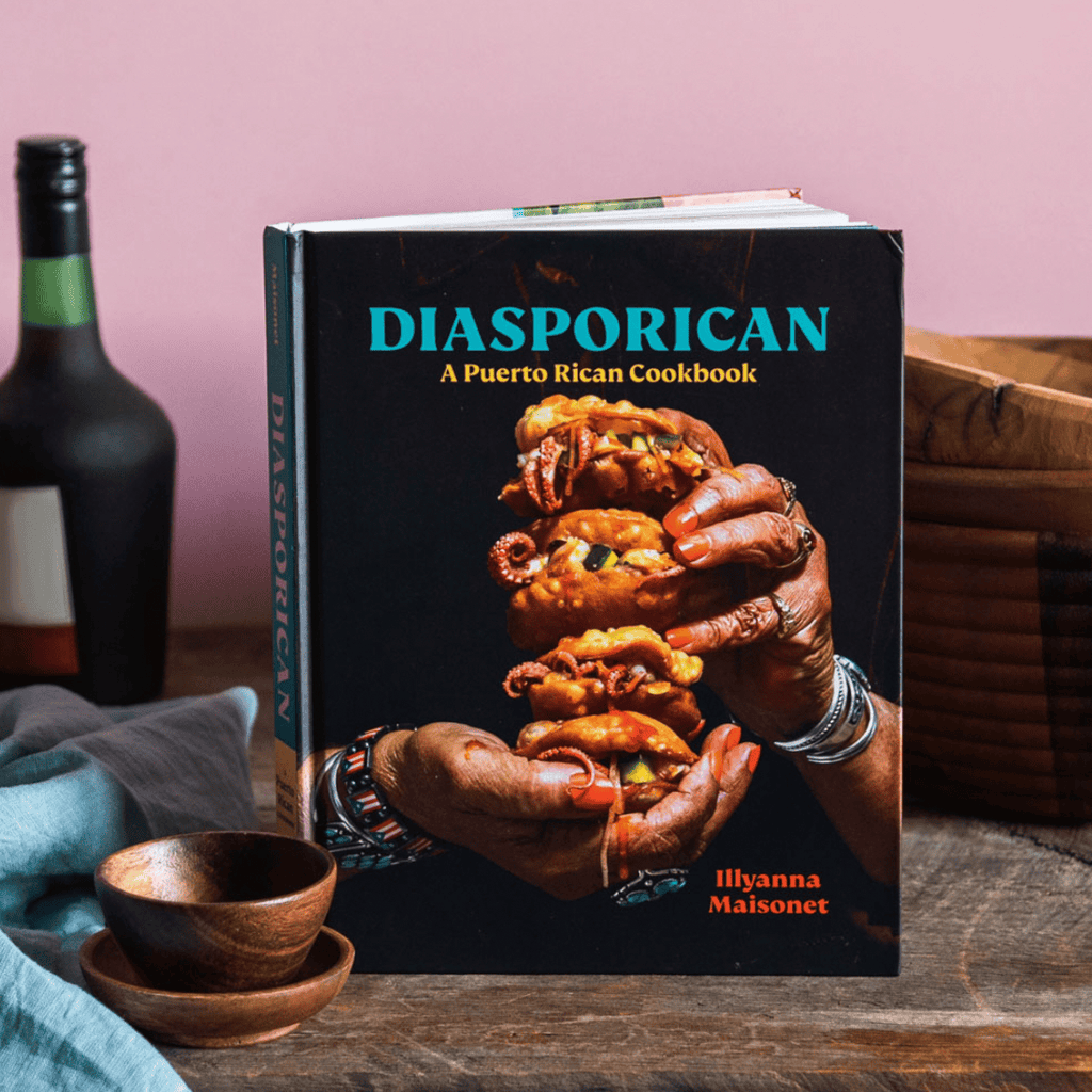 The image displays "Diasporican: A Puerto Rican Cookbook" by Gneiss Spice, featuring hands presenting authentic recipes on a wooden table with a bottle, bowl, and napkin.