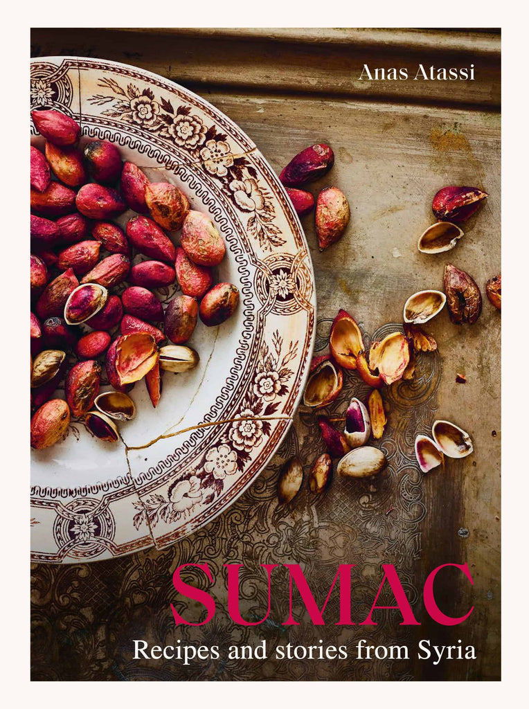 A decorative plate filled with vibrant red sumac, surrounded by cracked pistachios on an ornate tray, captures the essence of traditional Syrian cooking. The book "SUMAC: Recipes and Stories from Syria" by Anas Atassi from Gneiss Spice stands out in bold red letters.