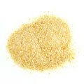 A small pile of light yellow, finely ground Gneiss Spice Onion (Granules) — USA Grown is spread on a white surface, resembling cornmeal or a similar grain.