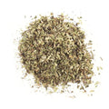A pile of dried, finely chopped green and brown Oregano Leaf from Gneiss Spice on a white background, perfect for adding organic oregano flavor to Mediterranean recipes.