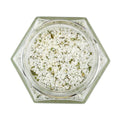 Coarse salt with green herb flakes in a hexagonal glass jar, seen from above
